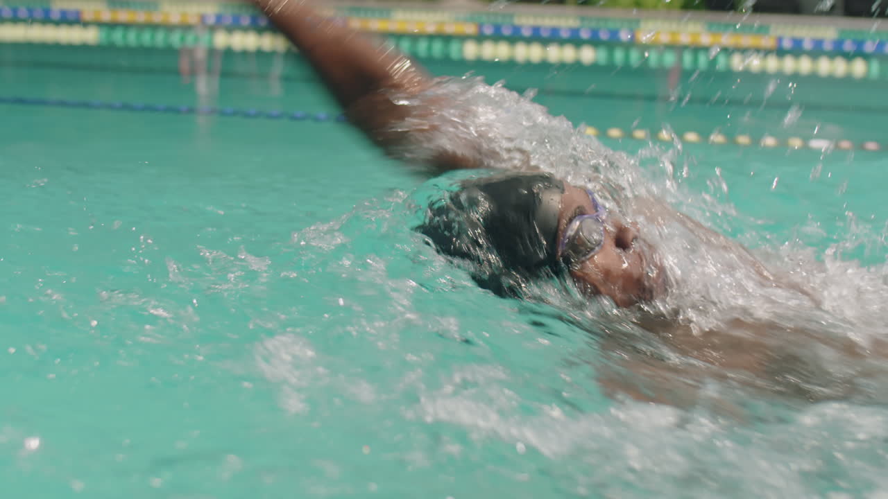 African American Athlete Swimming Backstroke in Outdoor Pool