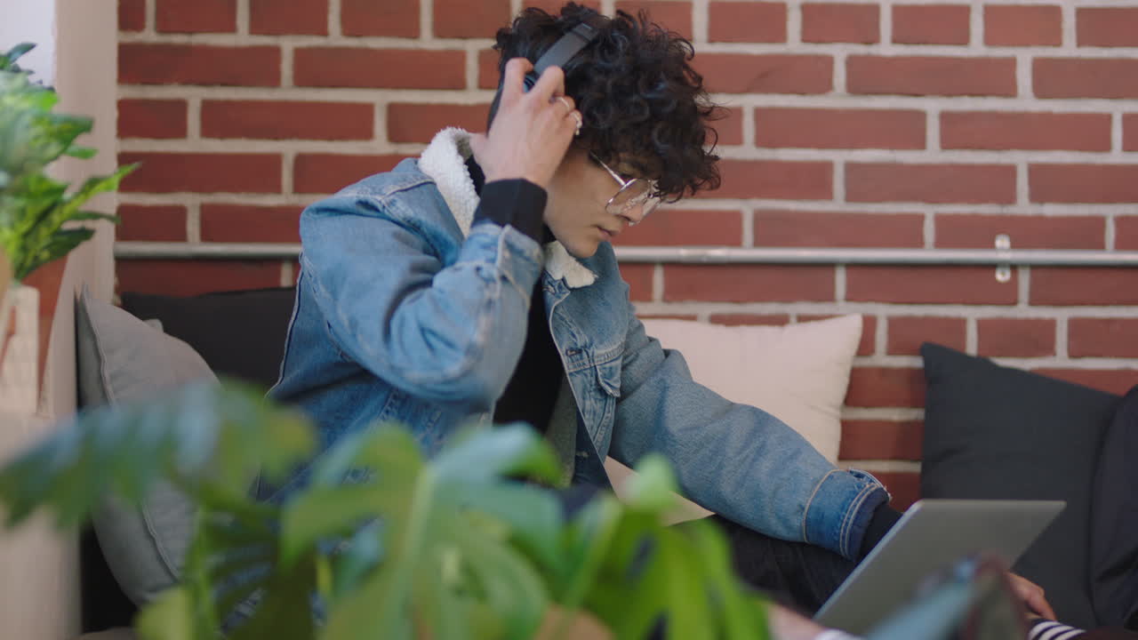 joven estudiante de negocios hispano usando computadora portátil estudiando en línea disfrutando de trabajar escuchando música relajándose en un moderno lugar de trabajo de oficina usando auriculares