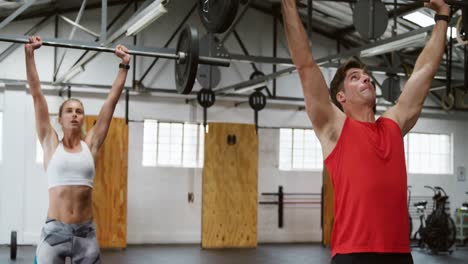 Front-view-of-an-athletic-Caucasian-man-and-woman-training-with-barbells