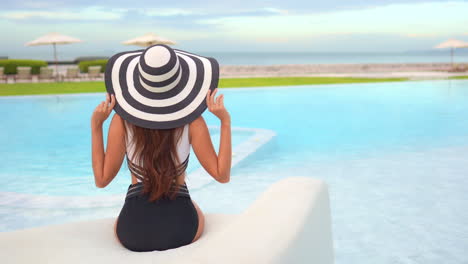 an attractive woman relaxing by a swimming pool at a luxury hotel resort