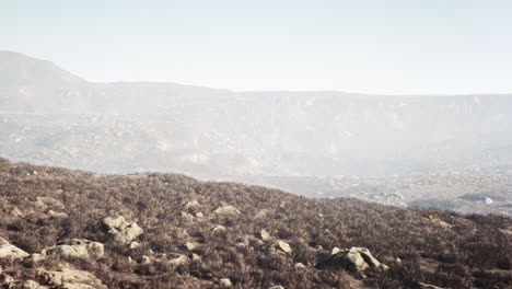 a scenic view of a mountain range with dry grass and rocky terrain