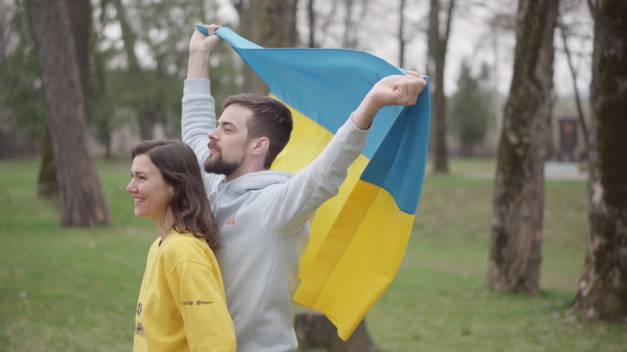Девочка и мальчик держат и несут украинский флаг. Символ эмпатии. Надпись на свитере девочки: "Ваше мнение важно"