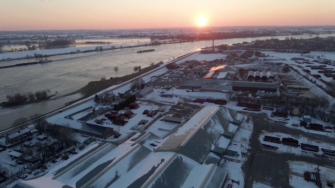 аэрофотоснимок промышленной местности с грузовым судном на реке с заходящим солнцем на заднем плане