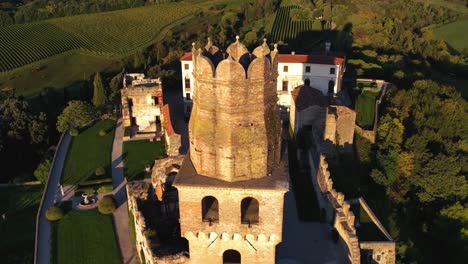 Aerial-view-of-a-medieval-castle-on-top-of-a-hill,-surrounded-by-prosecco-vineyards,-in-Italy
