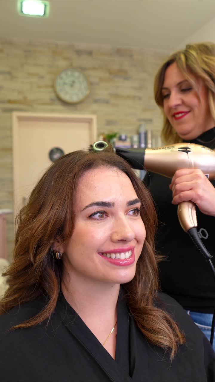 Mujer feliz secándose y peinándose el cabello en un salón