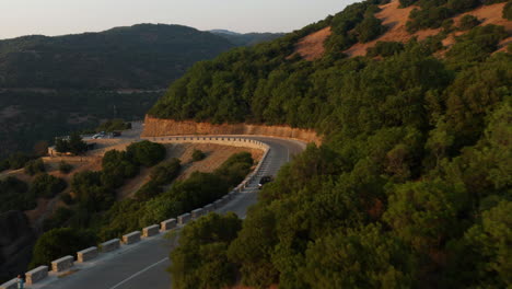 Aerial-View-Of-Car-Driving-Through-Mountain-Road-At-Sunset-Towards-The-Meteora-In-Greece