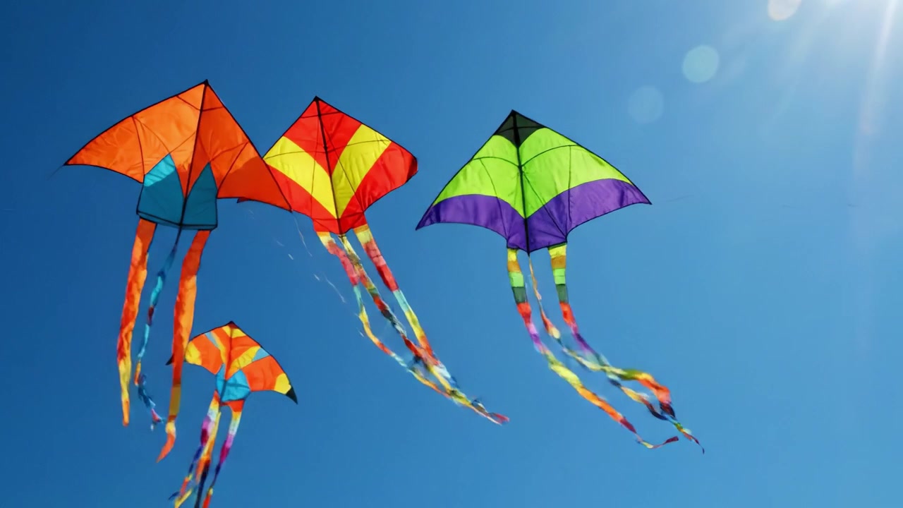 Aquiloni colorati si librano contro un cielo azzurro chiaro, danzando con la brezza e sfoggiando le loro code vivaci sotto la brillante luce del sole.
