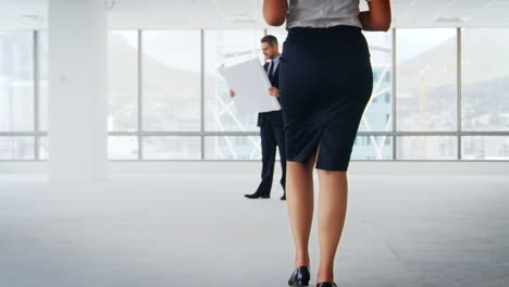 businesspeople meeting to look at plans in empty office