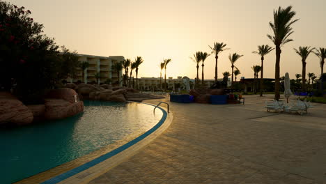 outdoor luxury hotel resort swimming pool at sunrise in egypt, early morning poolside dolly scene of empty garden pool area, tourism vacation and luxury