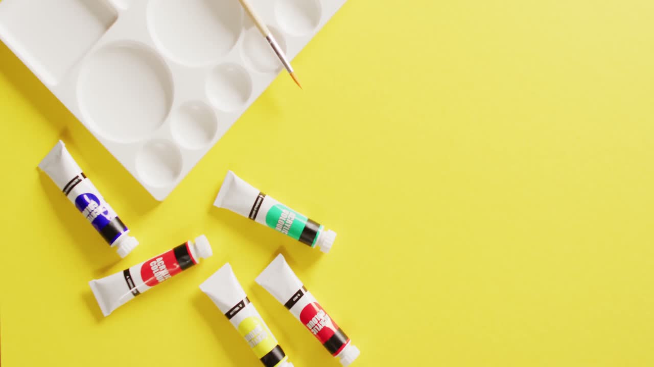 복사 공간과 함께 노란색 배경에 수색 페인트, 페인트 브러시 및 팔레트의 튜브의 비디오