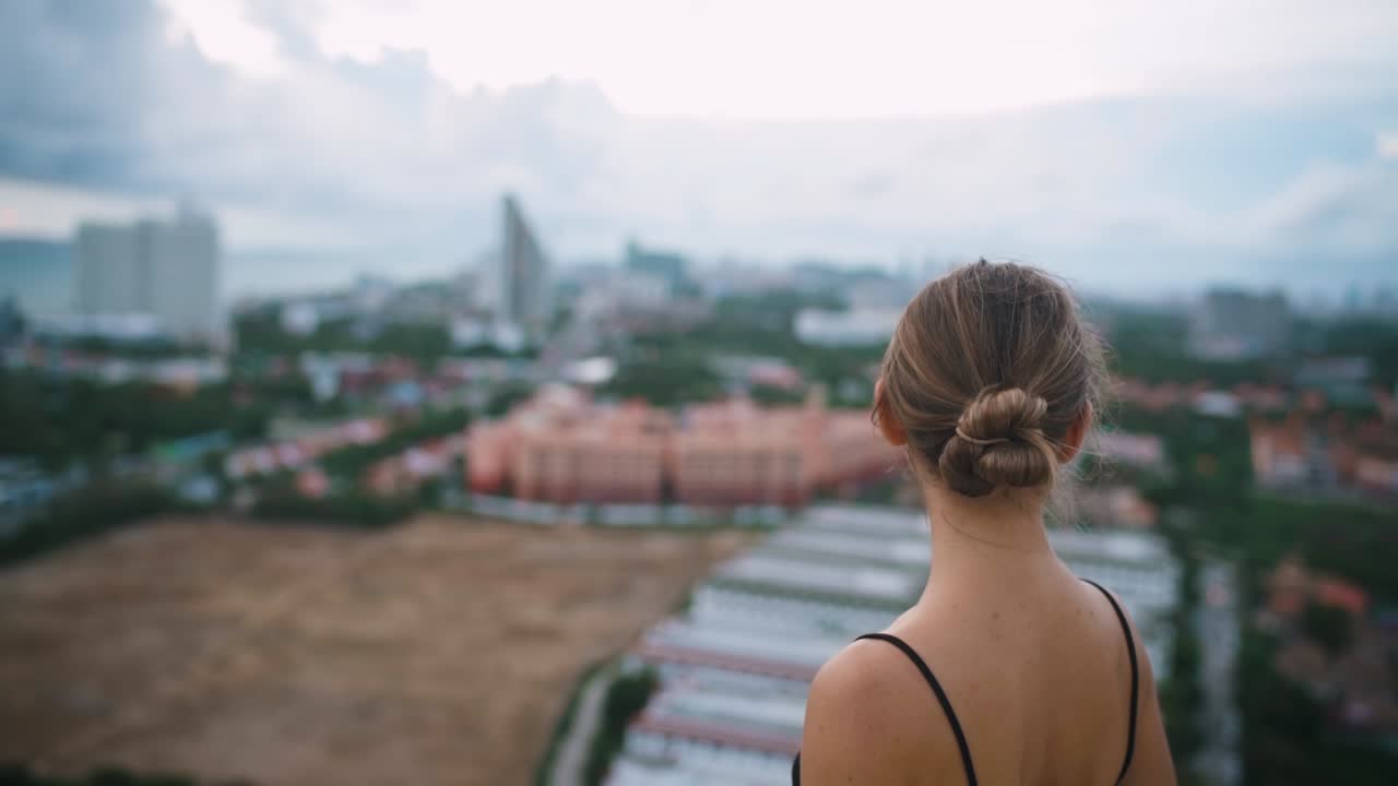 Close up portrait shot from back of young woman standing on roof and looking front
