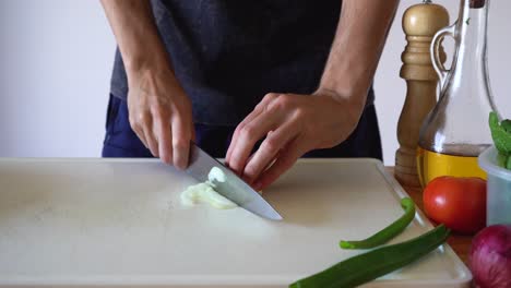 man's hands slicing white onion in the kitchen, close up