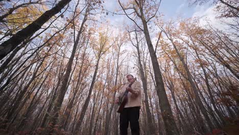 guy playing by the guitar in autumn background with yellow leaves in the park