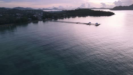 Panorámica-Aérea-De-Drones-Sobre-El-Océano-Azul-Hasta-El-Muelle-Durante-El-Amanecer