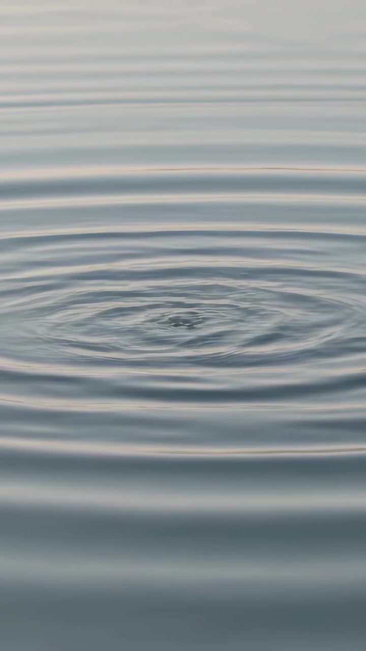 Video verticale: Creando increspature, uno schizzo centrale forma anelli che si diffondono e svaniscono sull'acqua calma