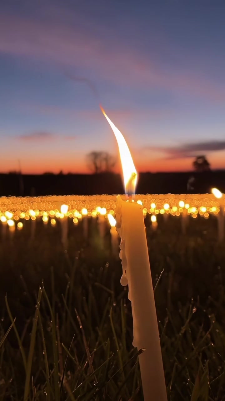 Candela che brucia in un campo al tramonto