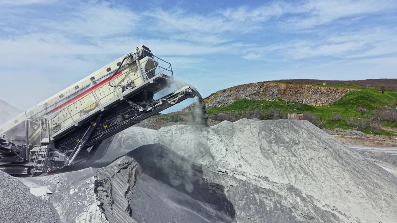 Granite quarry site with a rock crusher working on a bright day