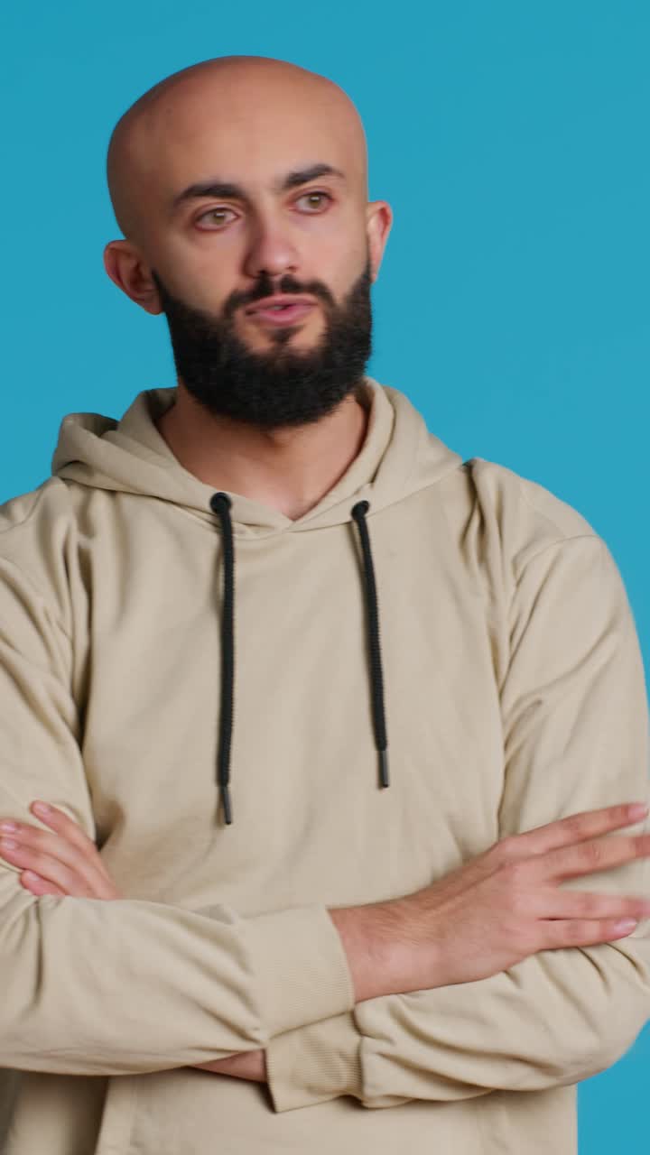 Vertical Video Young adult in a hoodie waiting for something in studio