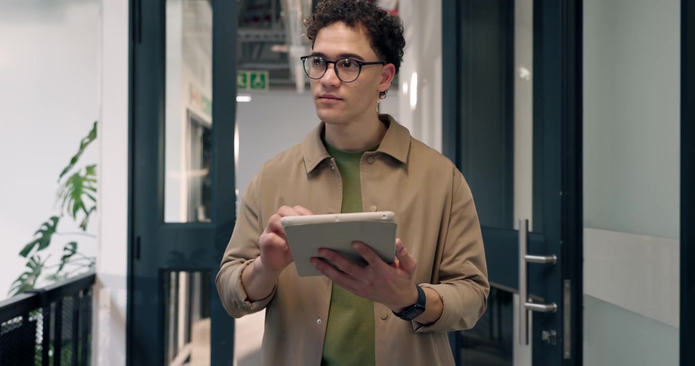 Ung mand går gennem kontorgang og bruger digital tablet