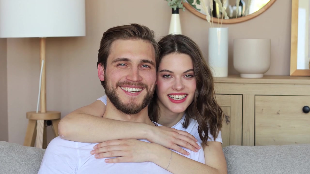 Casal jovem feliz se abraçando e sorrindo juntos em casa
