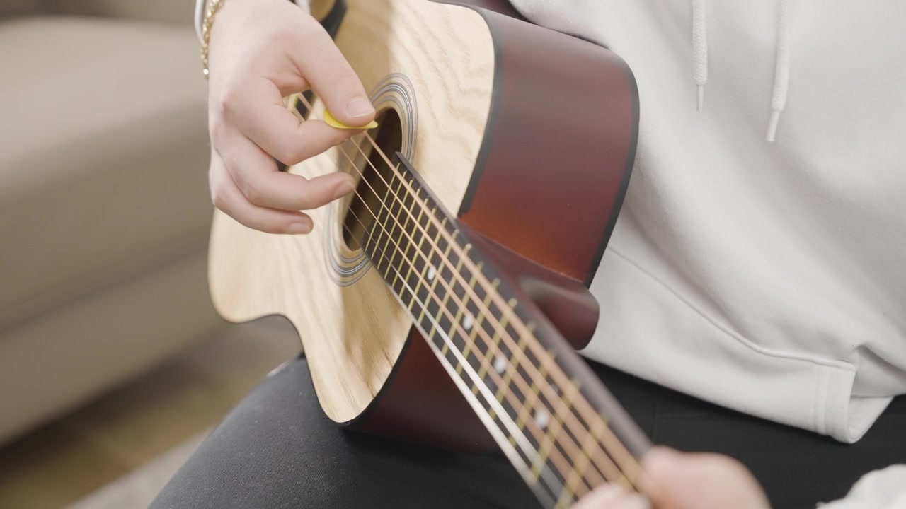 Young man strumming an acoustic guitar.