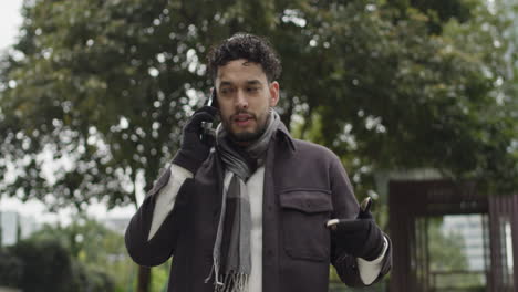 hombre caucásico hablando por teléfono usando un teléfono inteligente moderno para llamadas de negocios, usando ropa de invierno moderna, gestos de mano en cámara lenta hablando