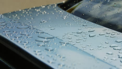 on a rainy day, large droplets of water decorate the surface of the car, glistening and reflecting the surrounding environment