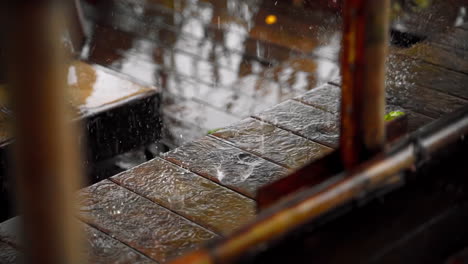 close-up of rain drops on wooden bench in slow motion