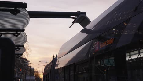 primer plano del autobús eléctrico que sale por la mañana después de cargar electricidad renovable en la estación de energía