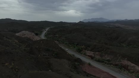 Imágenes-Aéreas-De-Drones-Siguiendo-A-Un-Automóvil-En-Una-Carretera-Solitaria-En-Un-Paisaje-Montañoso-En-Baluchistán