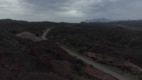aerial drone footage following a car on a lonely highway in a mountain landscape in balochistan