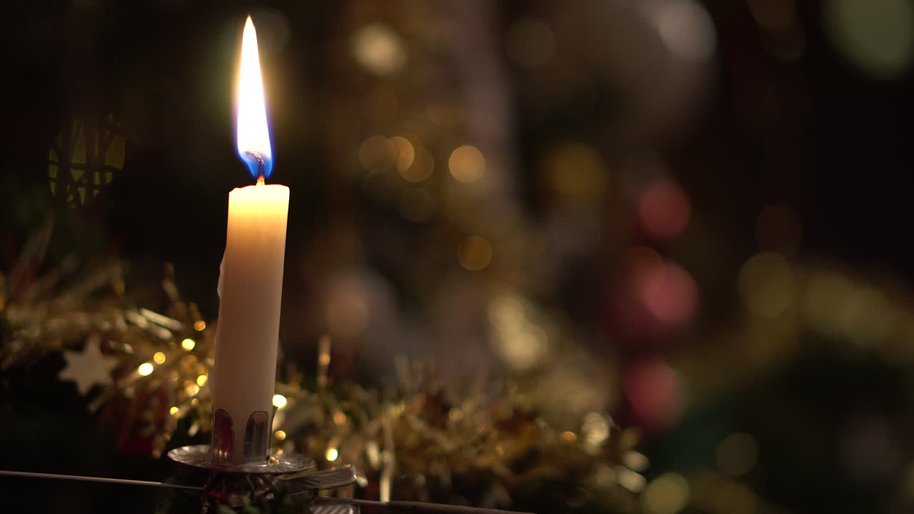 Blowing out a candle, mounted on a christmas tree in 4K.
