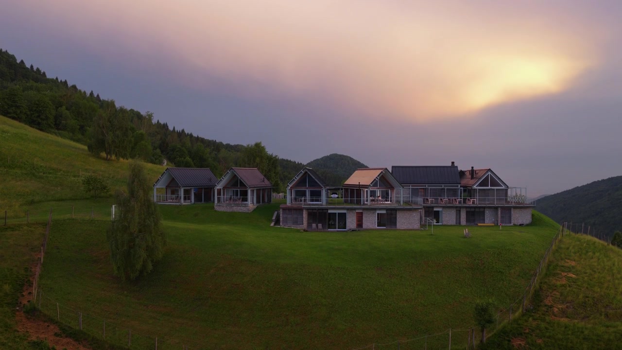 Naturskjønn utsikt over tradisjonelle trehytter plassert i fjellsidene ved solnedgang i Slovenia. Luftfoto med tilt nedover