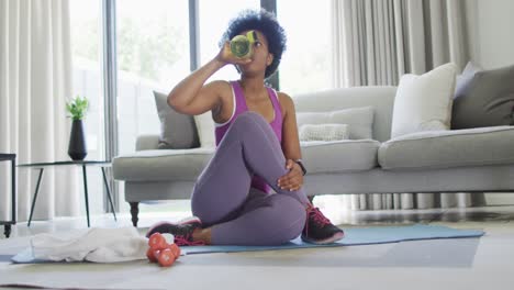 happy african american wearing sportswear, exercising, drinking water