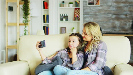 Kleines-Mädchen-Und-Ihre-Mutter-Sitzen-Auf-Der-Couch-Im-Wohnzimmer