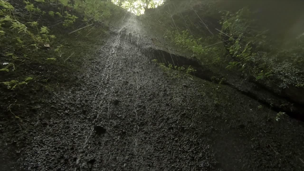 una fina y pequeña cascada que cae por las paredes rocosas y en la lente de la cámara