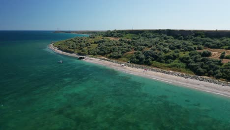 Eine-Ruhige-Küste-Mit-Klarem,-Blauem-Wasser-Und-Grüner-Landschaft-Unter-Einem-Strahlend-Sonnigen-Himmel