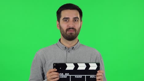 man holding clapperboard on green screen