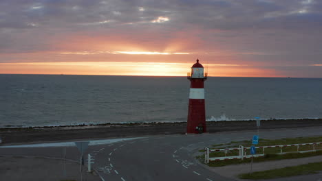 el faro de westkapelle durante una puesta de sol naranja brillante, con mucho viento