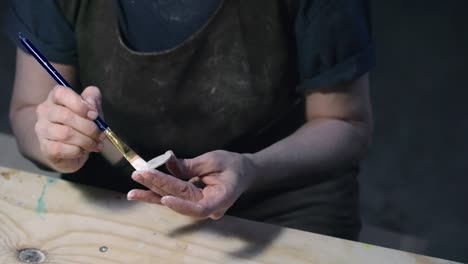 craftswoman painting wooden toy wheel