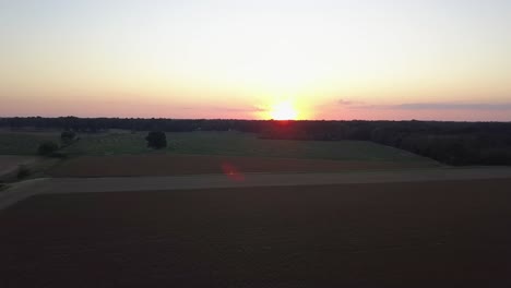 Wide-Aerial-View-of-Farm-Crop-Field-At-Sunset-Harvest-Countryside-Peaceful-Ending-Scene-Sunflare-Golden-Hour