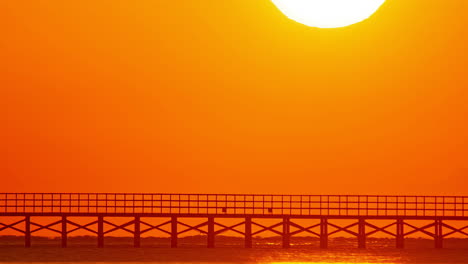 Salida-De-La-Luna-Contra-El-Cielo-Rojo-Cálido-Sobre-Un-Puente-De-Madera