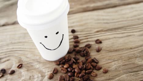 smiley face on disposable cup with coffee beans on sack