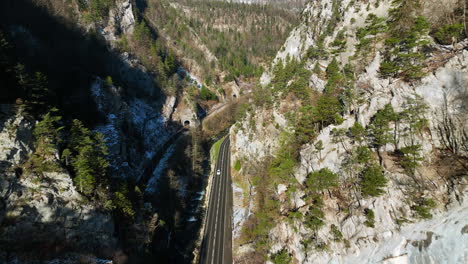 coches circulando por la carretera en las gargantas del jura en moutier en suiza junto a una vía férrea con túneles
