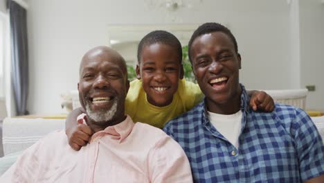 happy african american grandfather, father and son embracing on sofa