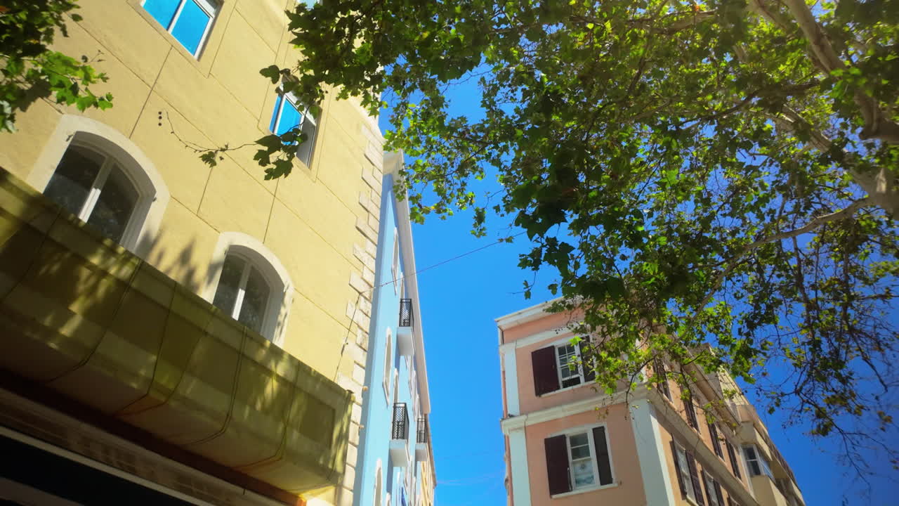 밝은 파란 하늘을 배경으로 초록색 나무로 둘러싸인 지브롤터의 다채로운 건물을 바라보고 있습니다.