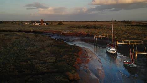 barcos de vela atracados en el canal del estuario con la noche con luz dorada