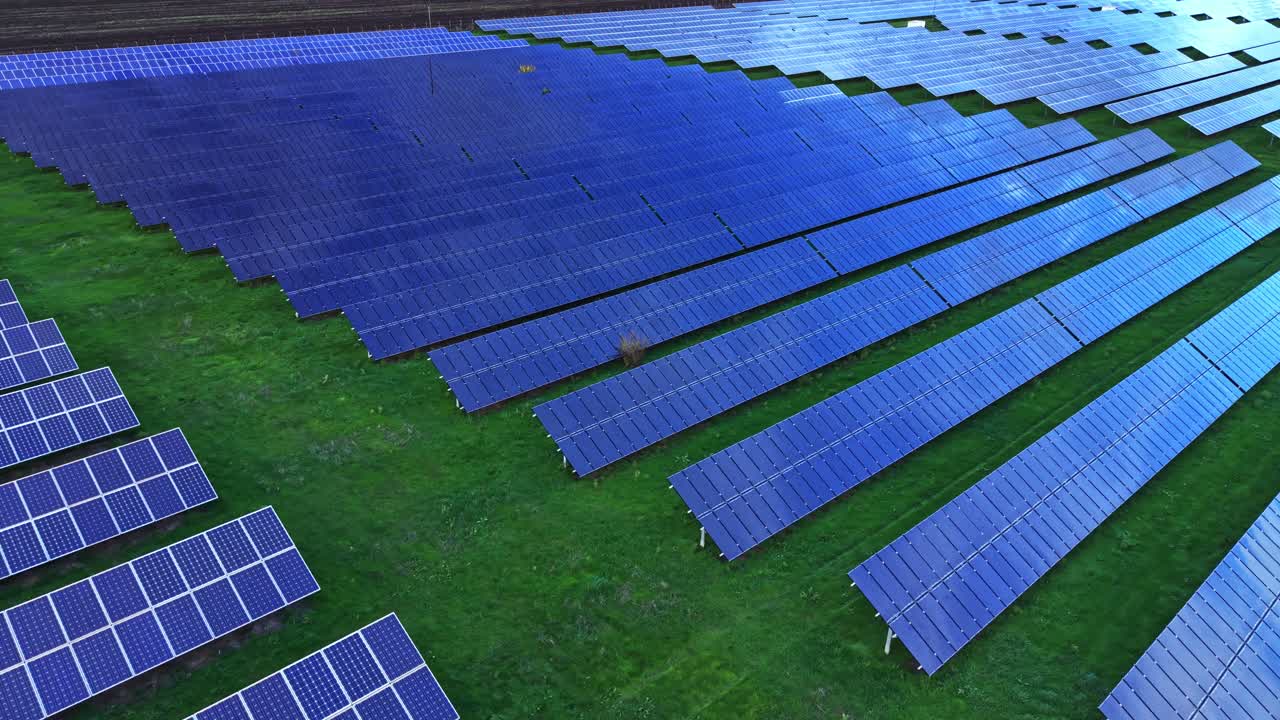 Vast solar panel array covers agricultural land in clear daylight