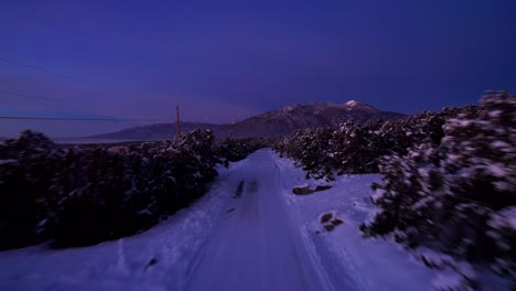 Aerial-drone-shot-over-a-road-revealing-a-large-mountain-range