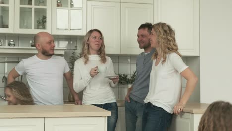 mujeres felices se comunican en la cocina con hombres, los niños se divierten corriendo
